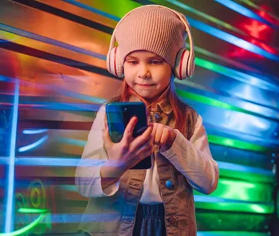 little girl wearing headphones using smartphone on the colorful neon