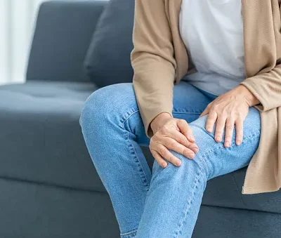 woman suffering from knee pain sitting sofa in the living room mature woman suffering from